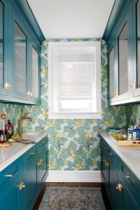 A pantry featuring glossy teal cabinets, showcasing a modern and stylish storage solution. The cabinets have sleek handles and ample shelving, with some items neatly organized on display.