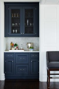 A farmhouse kitchen featuring indigo cabinets, creating a warm and inviting atmosphere. The cabinets have a rustic finish and are complemented by wooden countertops and farmhouse-style decor.