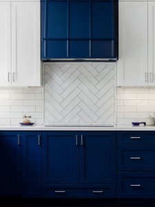 Elegant navy kitchen cabinets paired with a striking chevron tile backsplash, creating a bold and modern kitchen design. The deep navy color adds sophistication, while the chevron pattern brings dynamic visual interest.