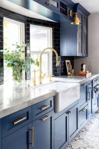 A stylish kitchen featuring navy cabinets paired with brass hardware, including elegant Olhar handles. The rich blue tones are complemented by warm brass accents, creating a sophisticated look.