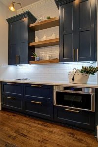 Ornate mahogany cabinets with blue accents and gold ornaments, creating a luxurious and sophisticated kitchen design. The rich wood tone is beautifully complemented by the vibrant blue and elegant gold details.