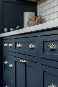 Slate blue cabinets featuring oversized cabinet knobs, adding a modern touch to a stylish kitchen design. The bold color and large knobs create a striking visual impact.